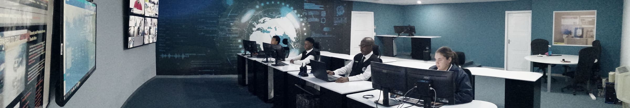 5.8:1 strip crop of the control room panorama: video wall left, operators at desks