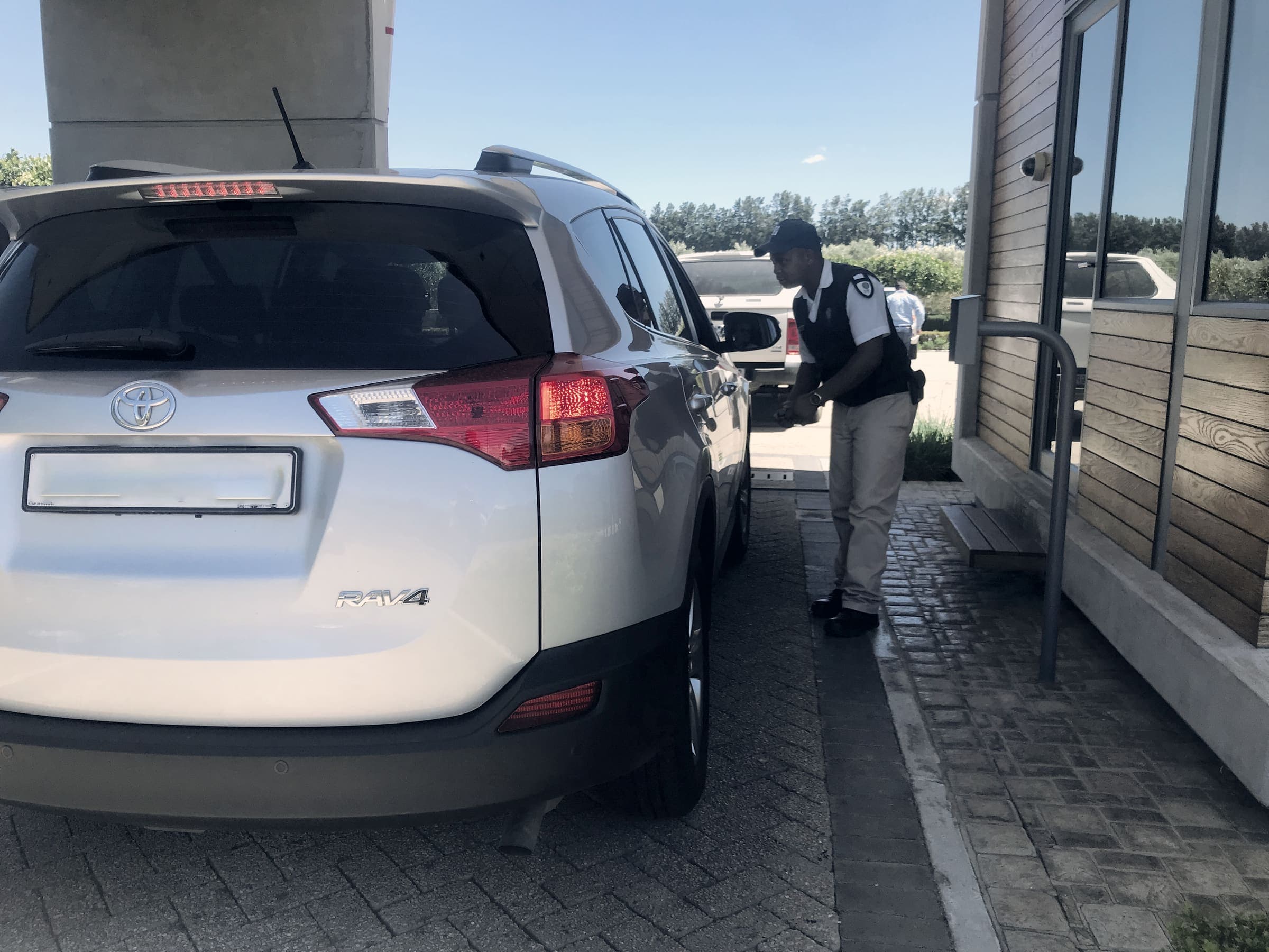 Guard checking an SUV at a gatehouse (plate blurred)
