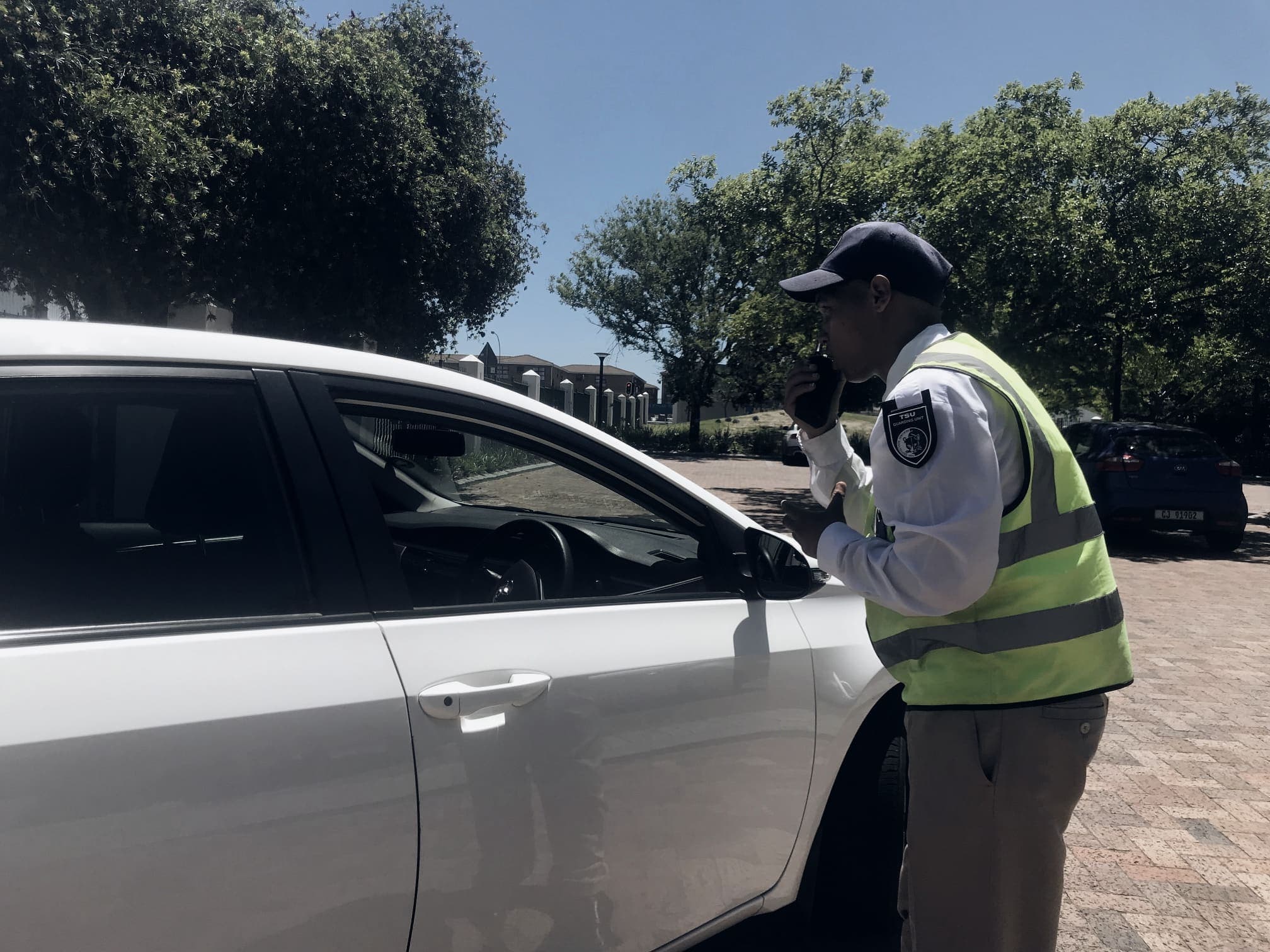Guard in hi-vis vest on radio at a car window