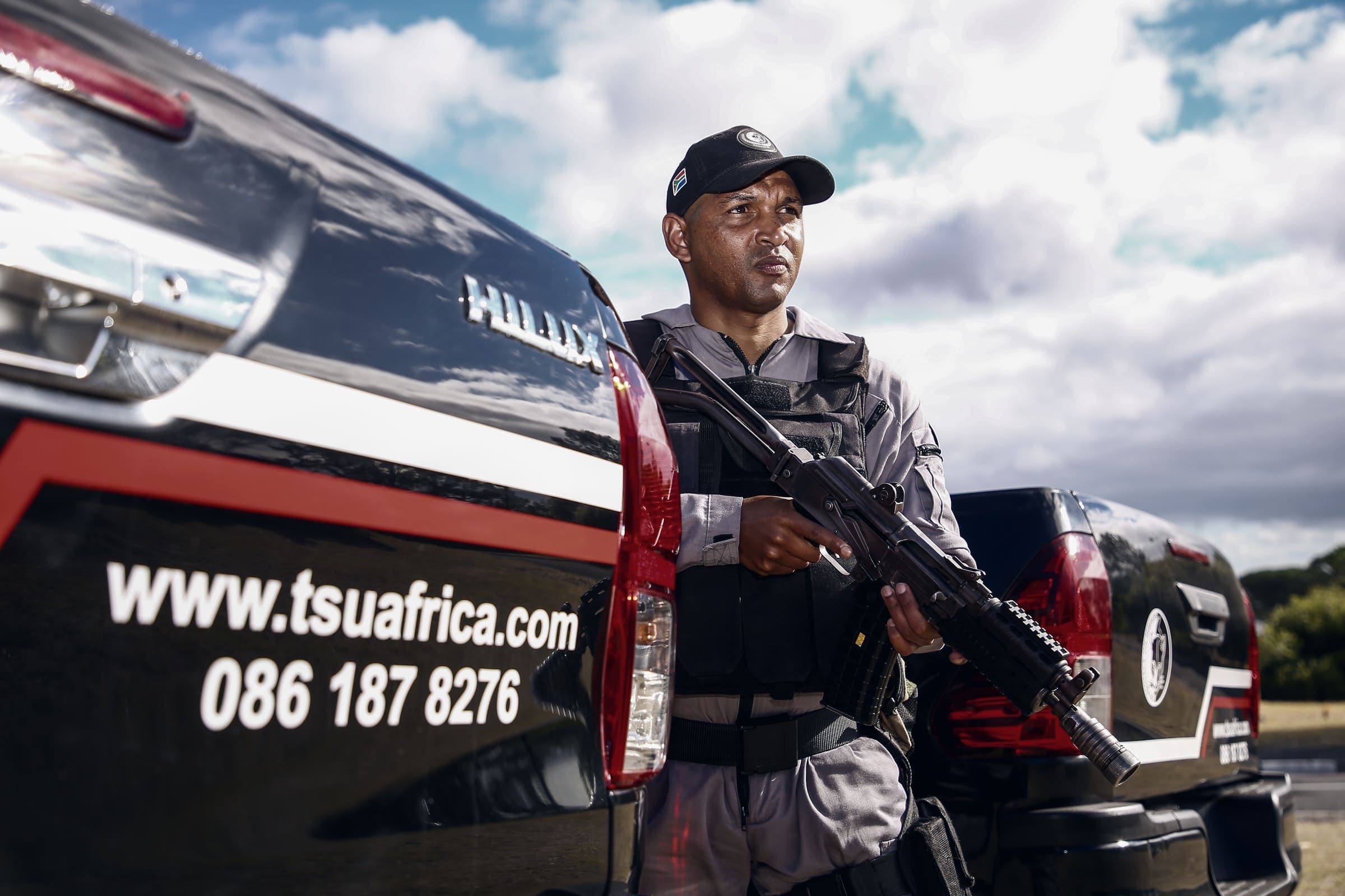 Armed officer beside vehicle printed www.tsuafrica.com 086 187 8276
