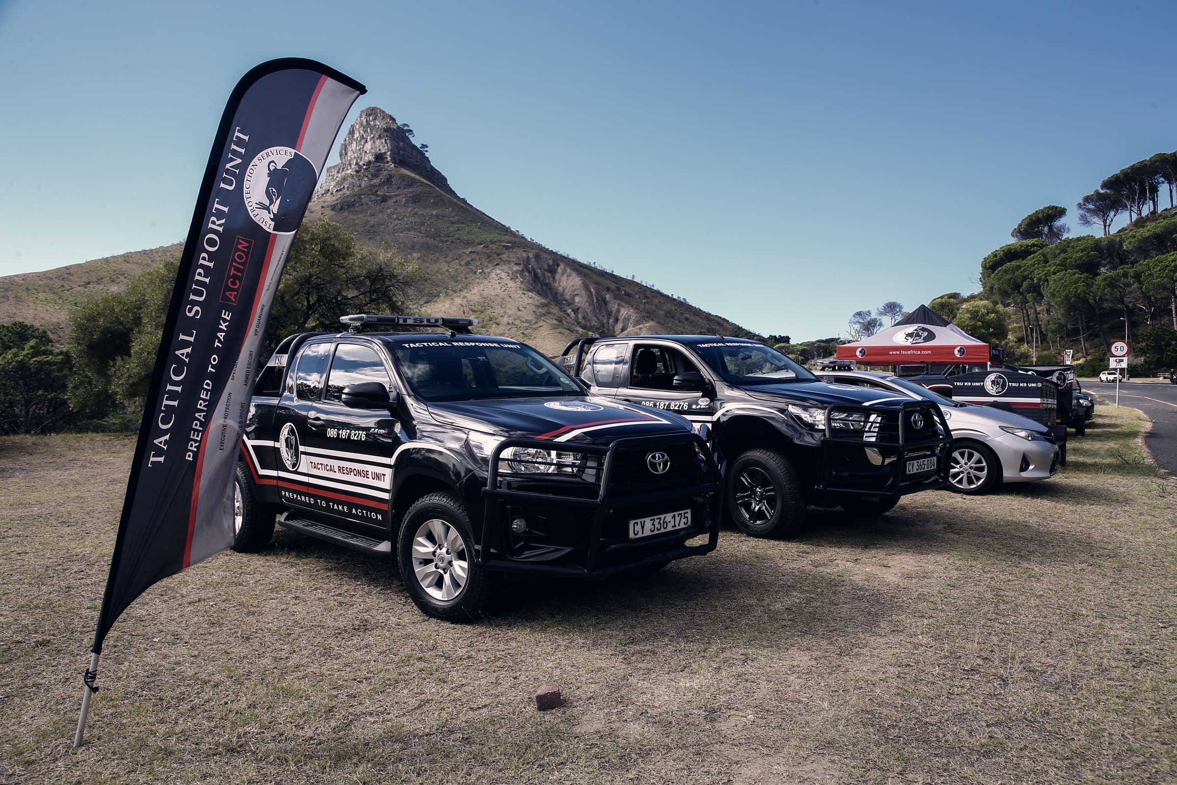 Branded TSU tactical bakkies and Tactical Support Unit flag banner, Lion's Head behind