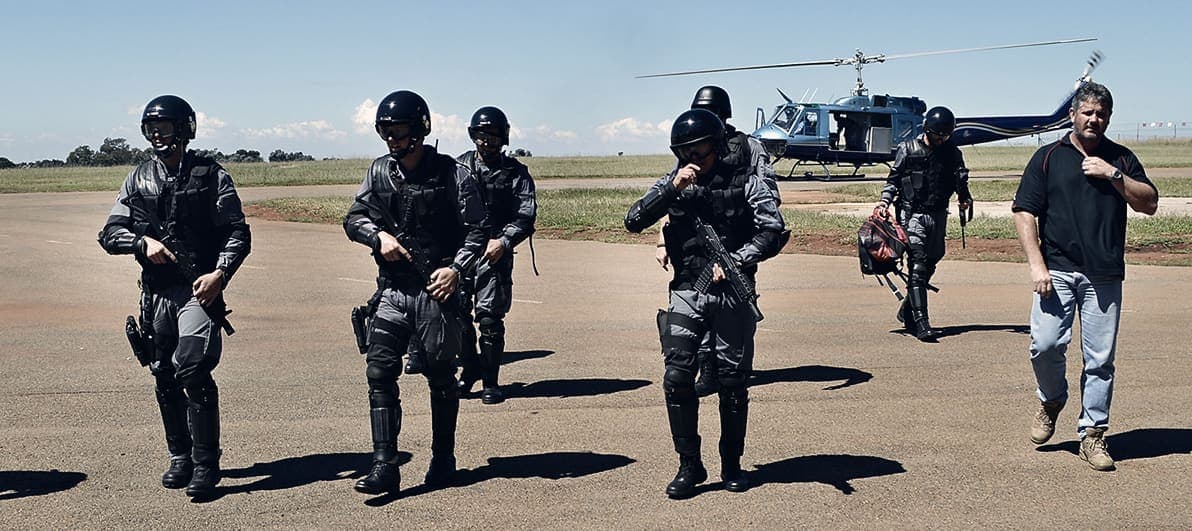 Tactical team walking from helicopter across an airfield (very wide, small)