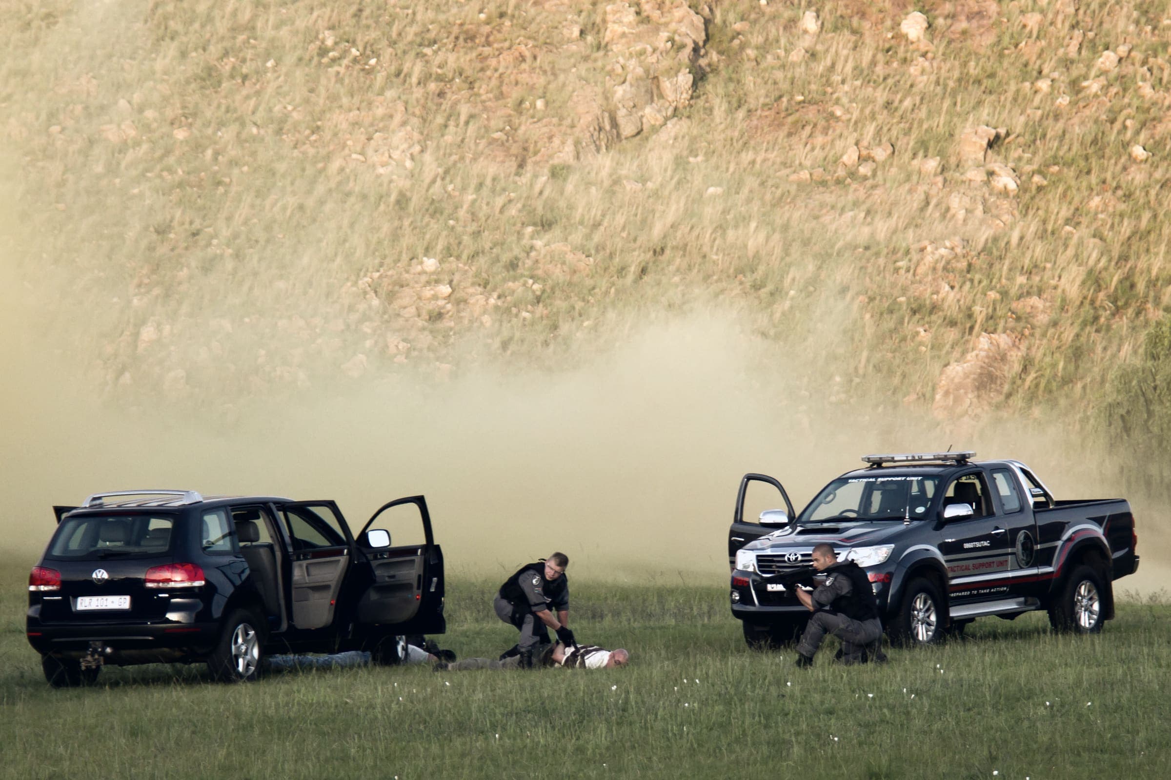 Two tactical vehicles, officers restraining suspects in smoke on grass (drill)