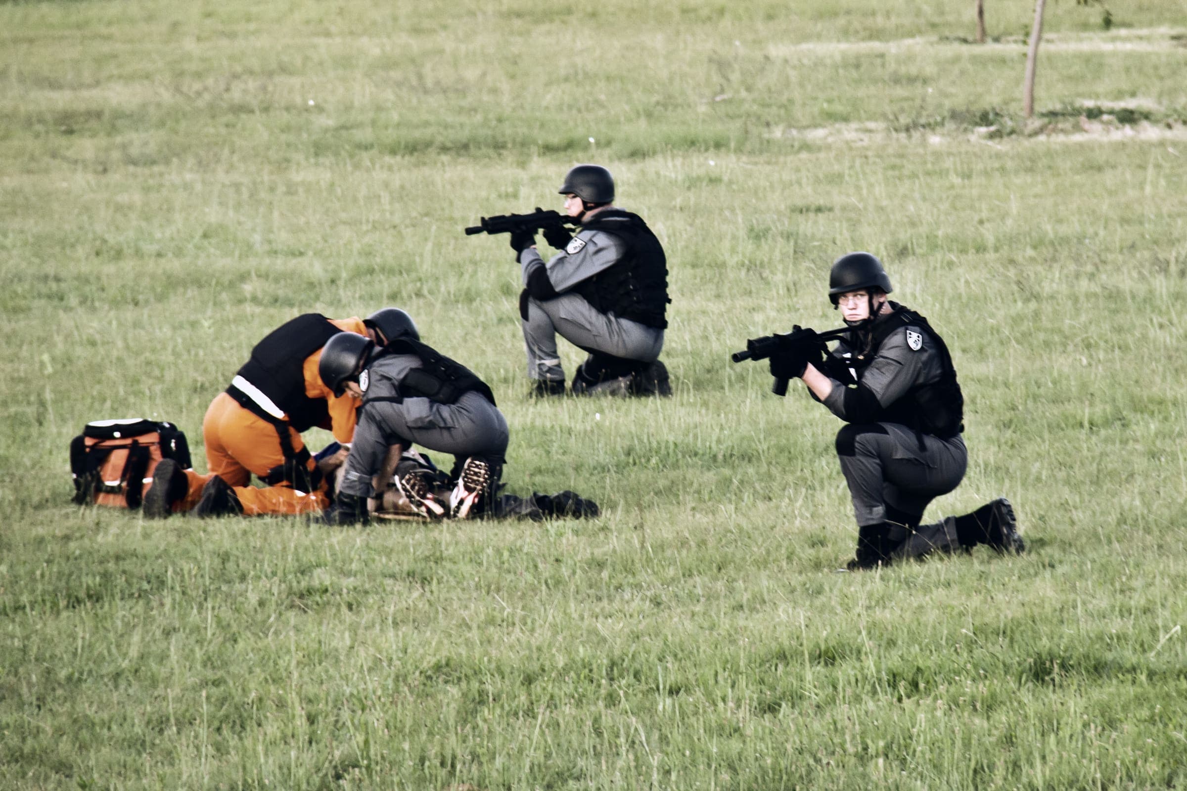 Field training: two officers covering a medic casualty drill on grass