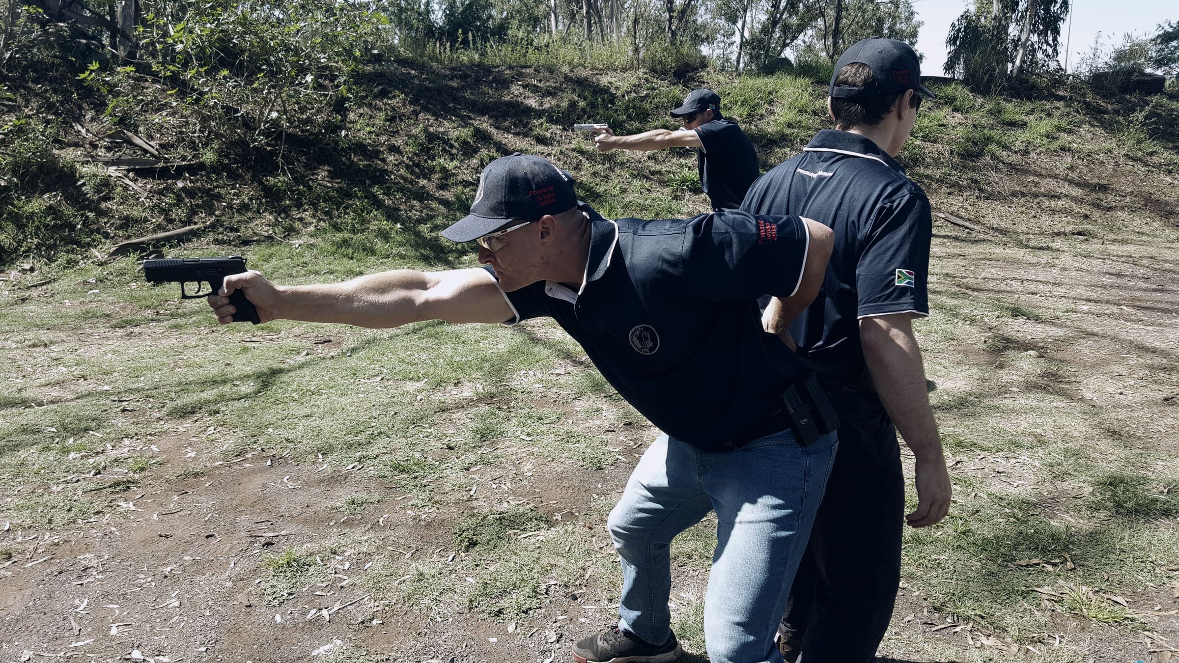 Instructor coaching a trainee at a pistol range